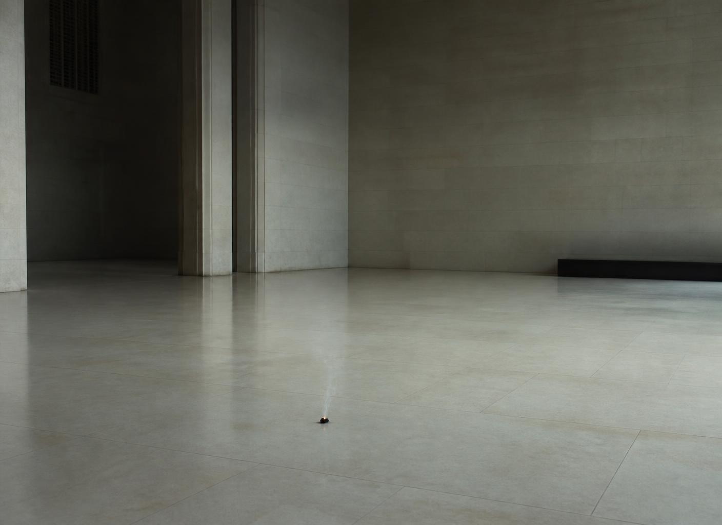 A small dormant ember on a wide empty stone floor in a quiet hall